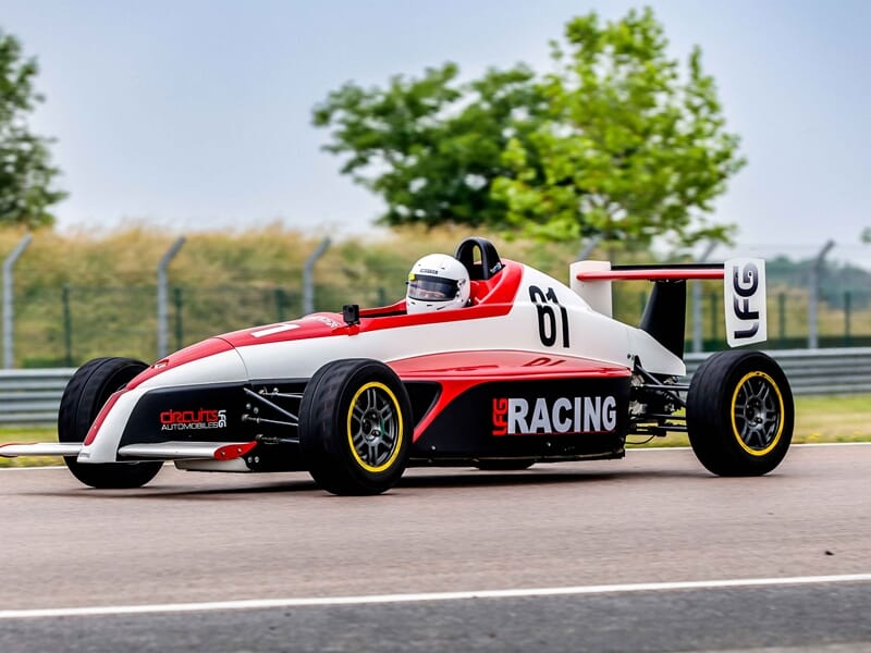 Voiture de course Formule Renault au circuit de Pont l'Evêque, pilote casqué en pleine conduite sportive.