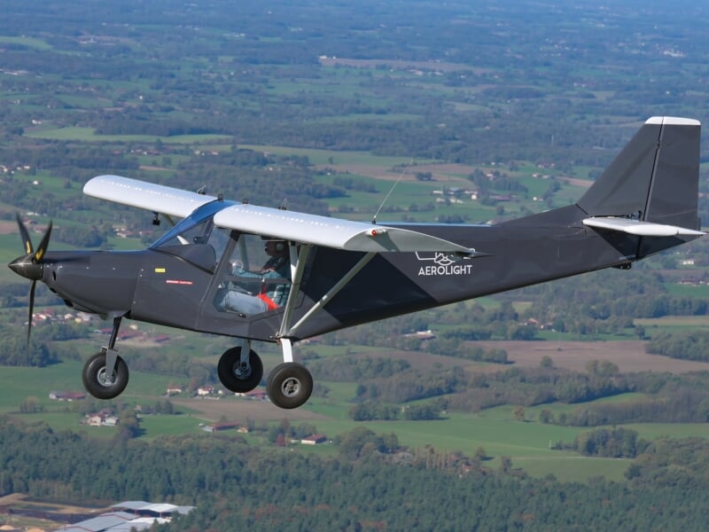 Avion léger noir en vol avec le logo