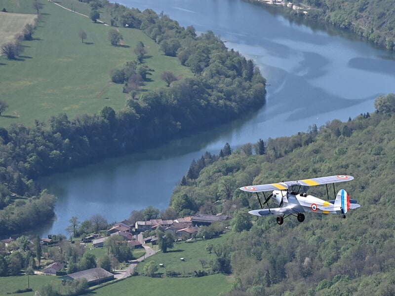 Avion biplan Stampe en vol au dessus d'une rivière