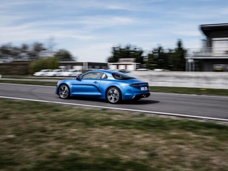 Alpine A110 sur circuit asphalte, coaching pilotage avec pilote casqué en action.