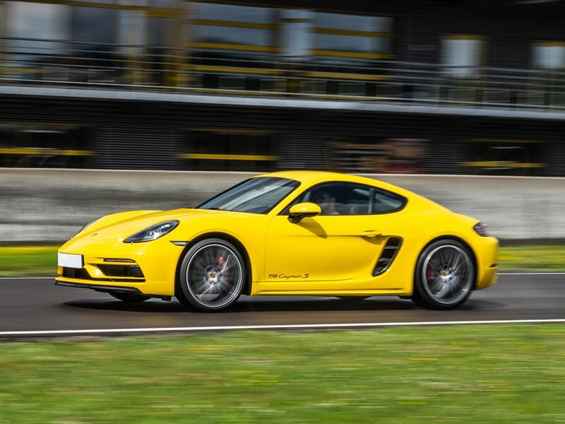 Voiture de sport jaune Porsche 718 Cayman S roulant rapidement sur un circuit d'asphalte à Andrézieux-Loire.