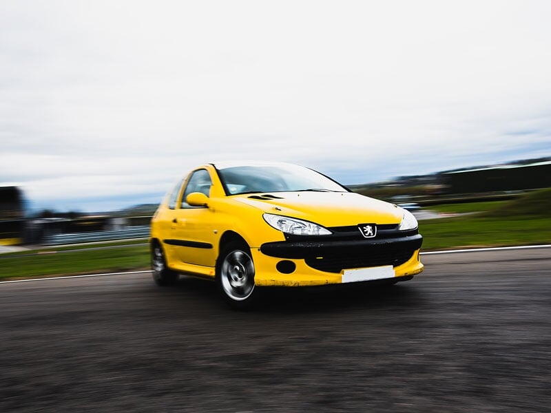 une peugeot 206 jaune en plein dérapage sur un circuit de course