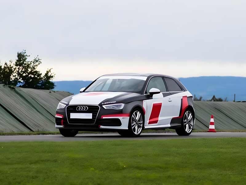 Voiture sportive Audi A3 Cup noire et blanche avec motifs rouges sur circuit d'asphalte à Andrézieux en Loire