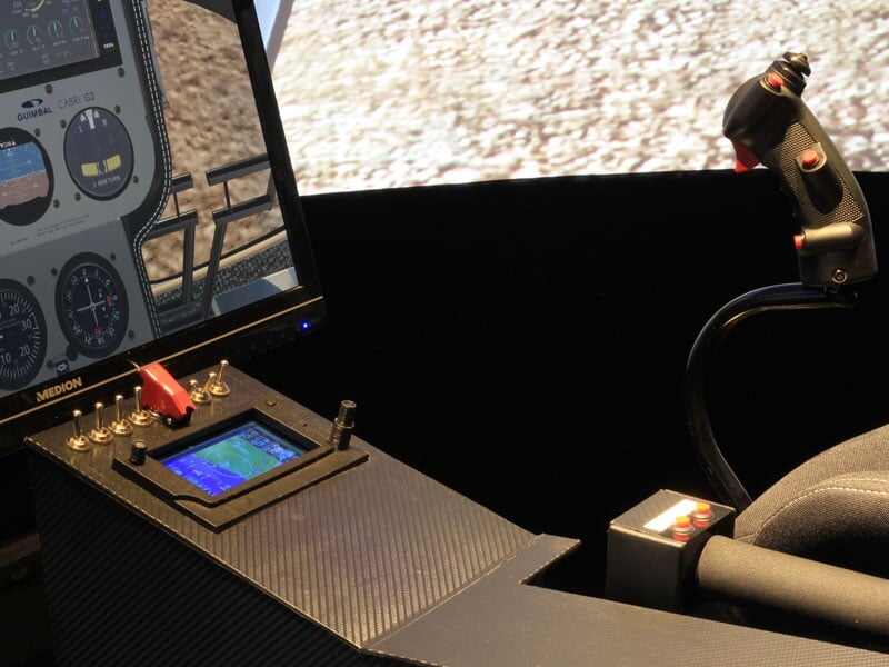 Vue rapprochée du tableau de bord d'un simulateur de pilotage d'avion avec écran et commandes diverses.