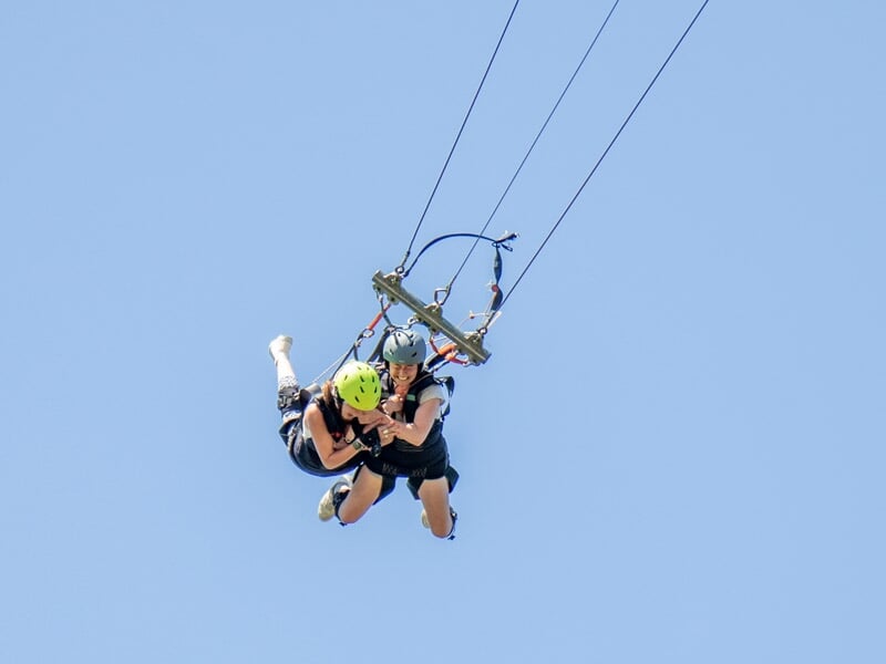 Deux personnes en chute libre lors d'un saut à l'élastique, avec le ciel bleu clair en arrière-plan