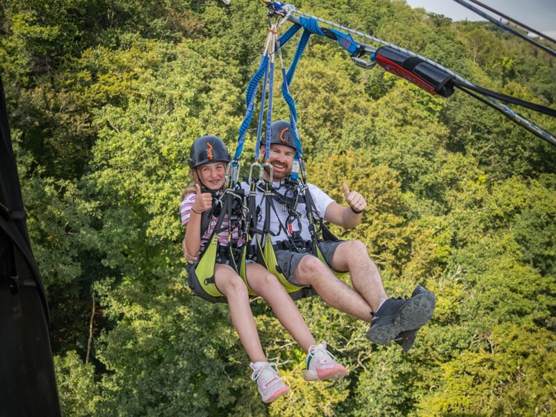 Une jeune fille et son père en pleine descente lors d’un saut pendulaire, visiblement amusés et profitant de l’adrénaline