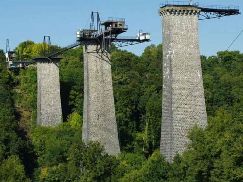 Vue du viaduc de la Souleuvre avec ses piliers en pierre et la plateforme de saut à l'élastique au sommet.