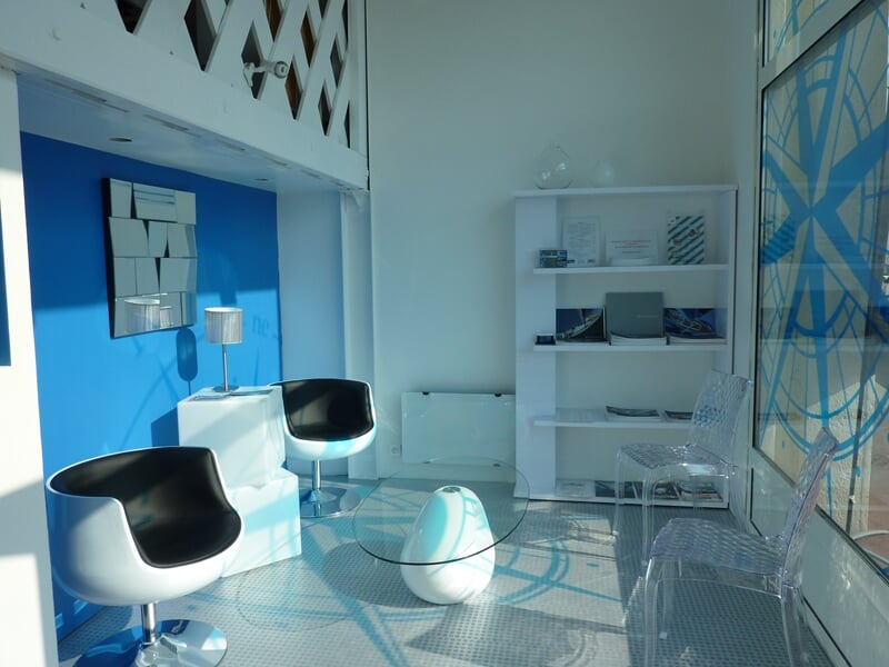 Intérieur lumineux d'un espace moderne avec chaises blanches et bleues et décoration épurée.