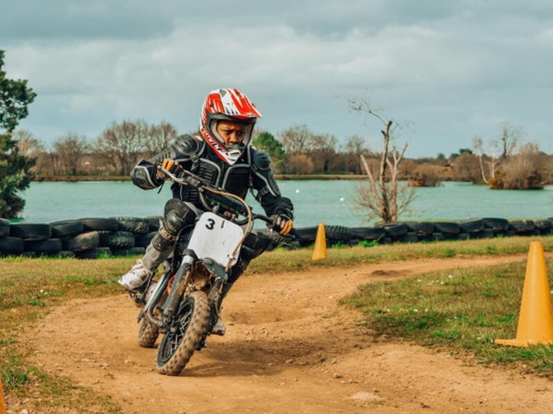 Adolescent pratiquant la mini moto devant un lac