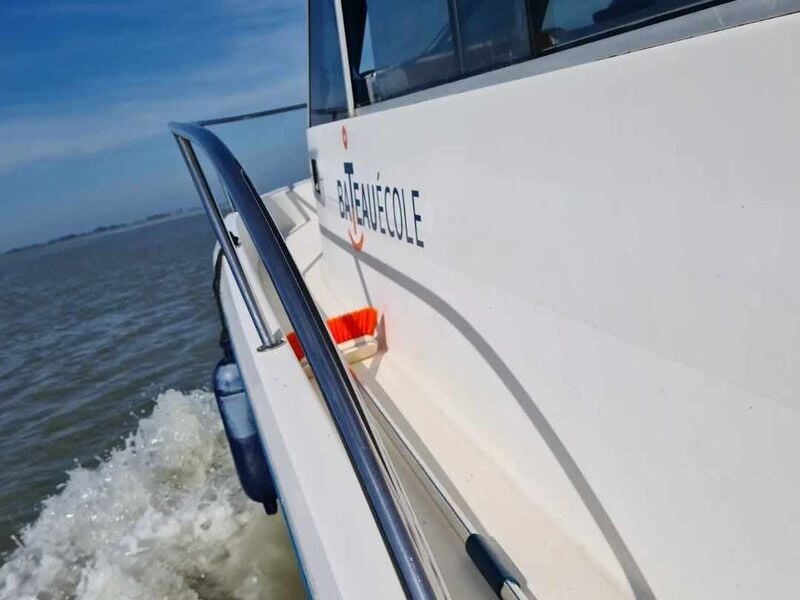 Vue rapprochée d'un bateau en mouvement sur l'eau avec l'inscription 'BATEAU ECOLE' visible sur la coque.