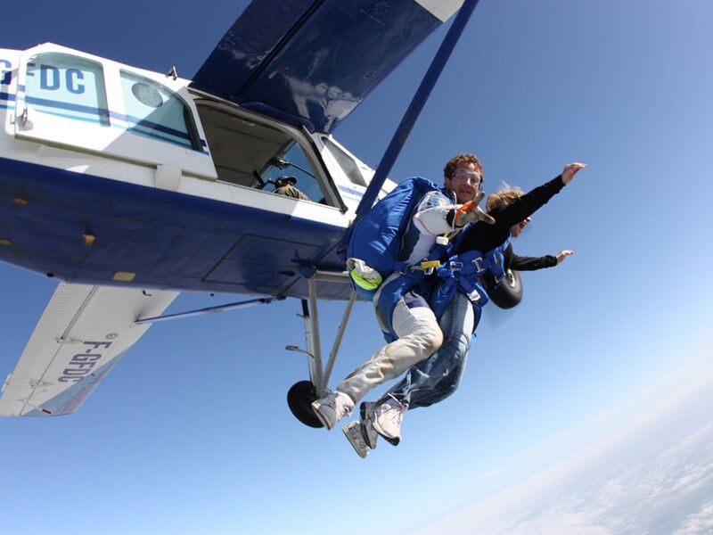 Expérience inoubliable de parachutisme tandem avec un instructeur et son élève s'élançant depuis un avion en plein vol. Attachés ensemble, ils plongent dans le ciel, prêts à vivre un moment riche en é