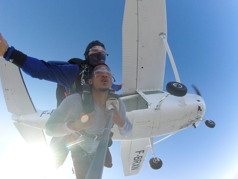 Départ en parachute en tandem, vue en contre-plongée sur un petit avion blanc au décollage.