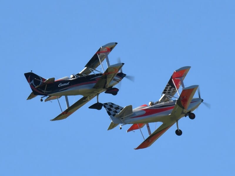 Deux avions acrobatiques volant en formation dans un ciel bleu clair lors d'un spectacle aérien