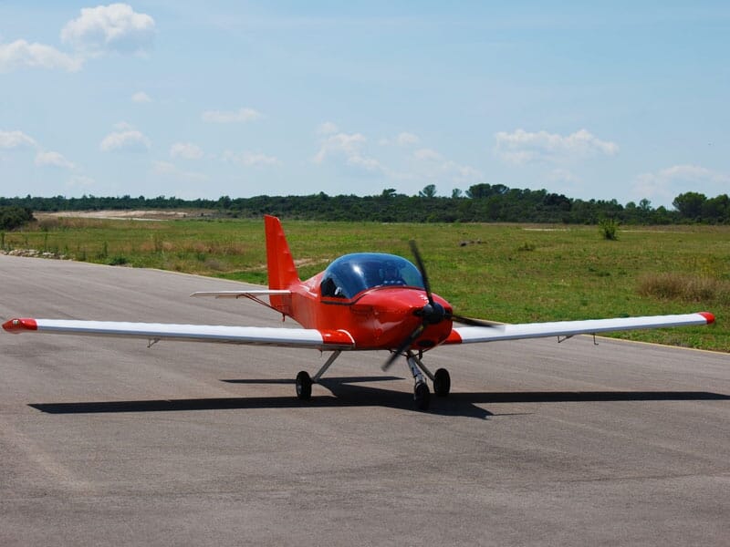 un avion rouge en plein décollage sur une piste d'aérodrome