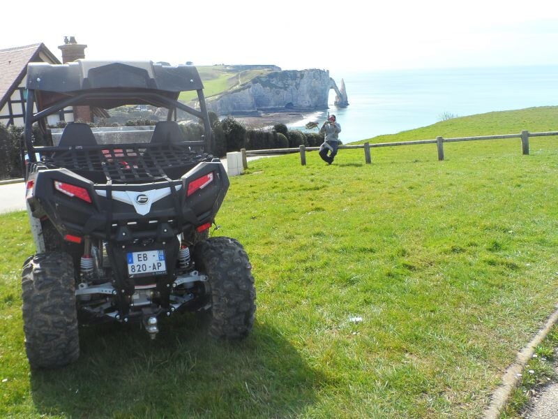 Quad garé sur une pelouse verte avec une falaise et la mer en arrière-plan sous un ciel clair.