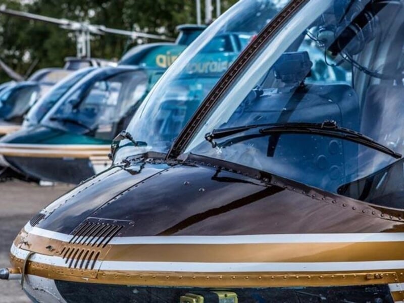 Gros plan sur plusieurs hélicoptères alignés, montrant leurs cockpits et pare-brises réfléchissants.
