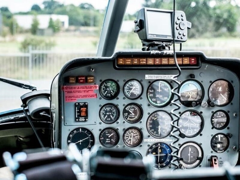Tableau de bord d'un hélicoptère avec de nombreux instruments de vol et un GPS fixé au-dessus.