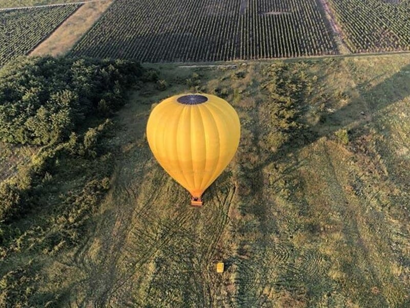 une montgolfière jaune posée au milieu d'un champ vue depuis le ciel