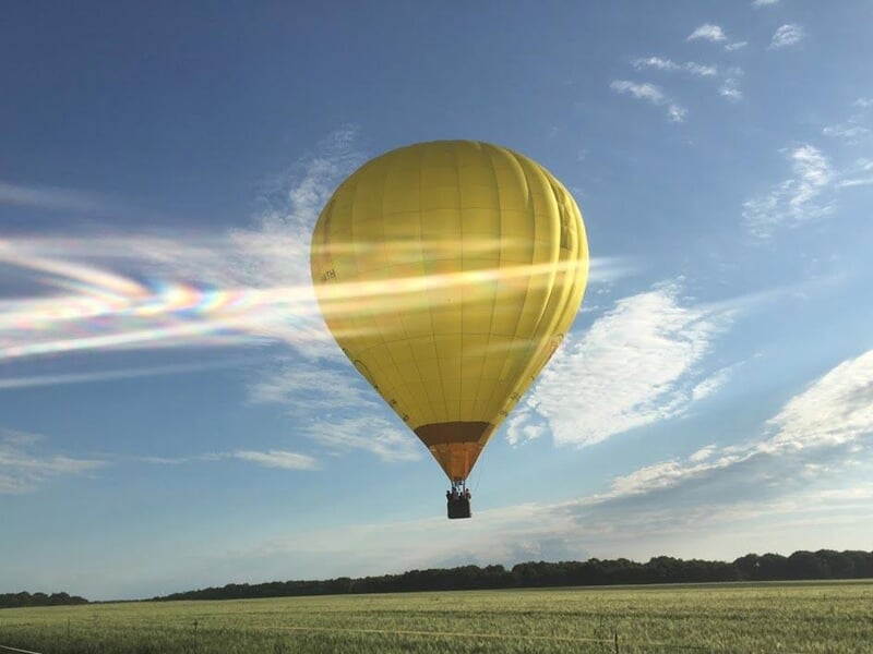 une montgolfière jaune survole un champ vert
