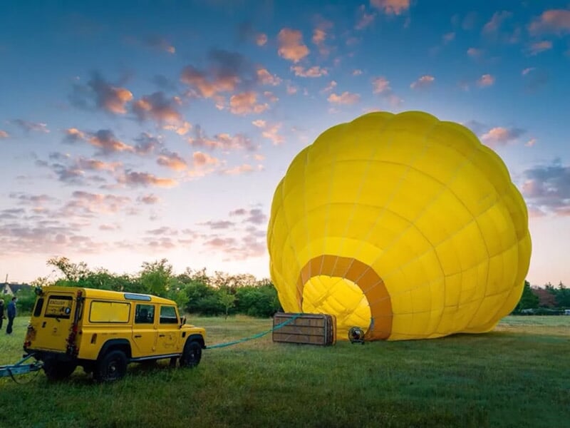 une montgolfière jaune en plein gonflage face à un 4x4 jaune