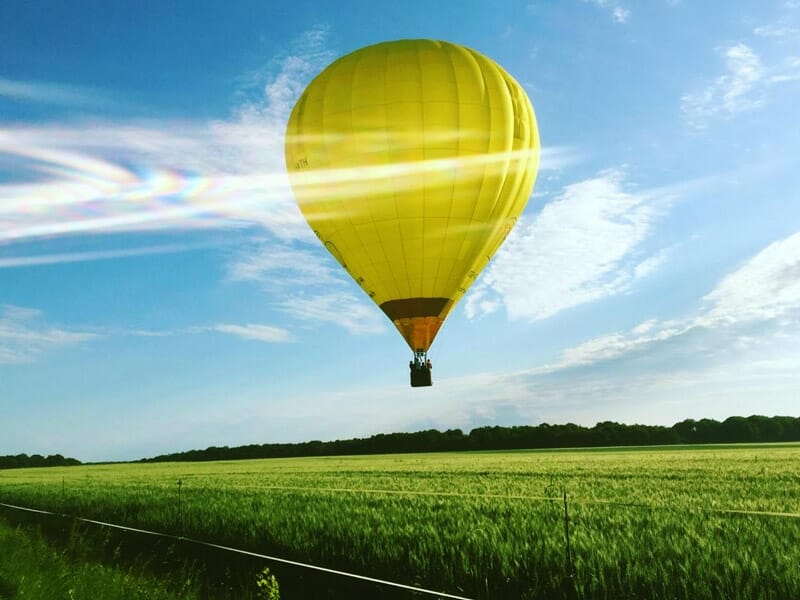 une montgolfière jaune survole un champ d'herbe