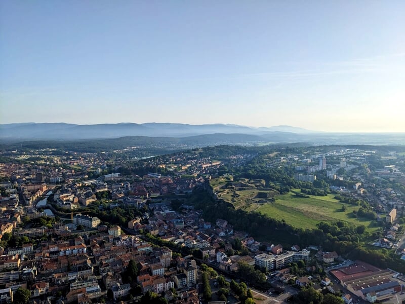 Vue aérienne d'une ville au crépuscule avec des bâtiments résidentiels et commerciaux et des collines en arrière-plan