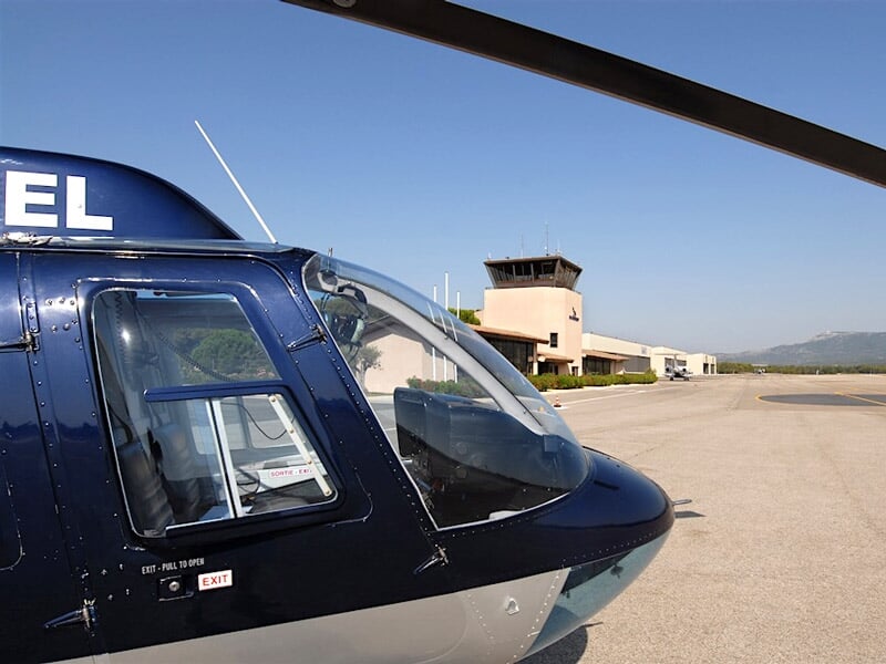 Gros plan sur le cockpit et le nez d'un hélicoptère stationné sur une piste d'aéroport par temps clair.