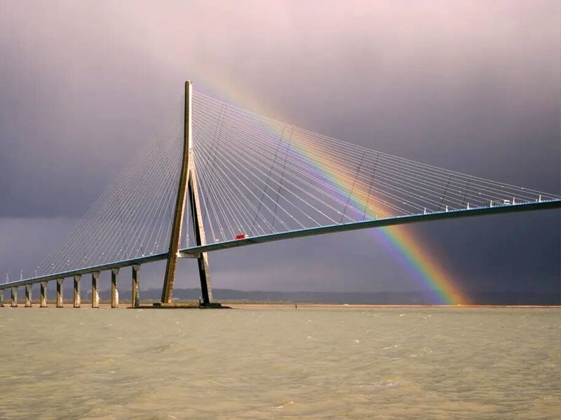 un arc en ciel se dresse derrière le Pont de Normandie