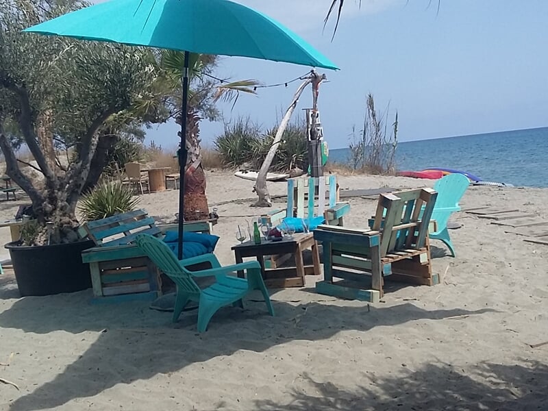 Chaises et parasol turquoise sur une plage de sable fin avec vue sur la mer calme.