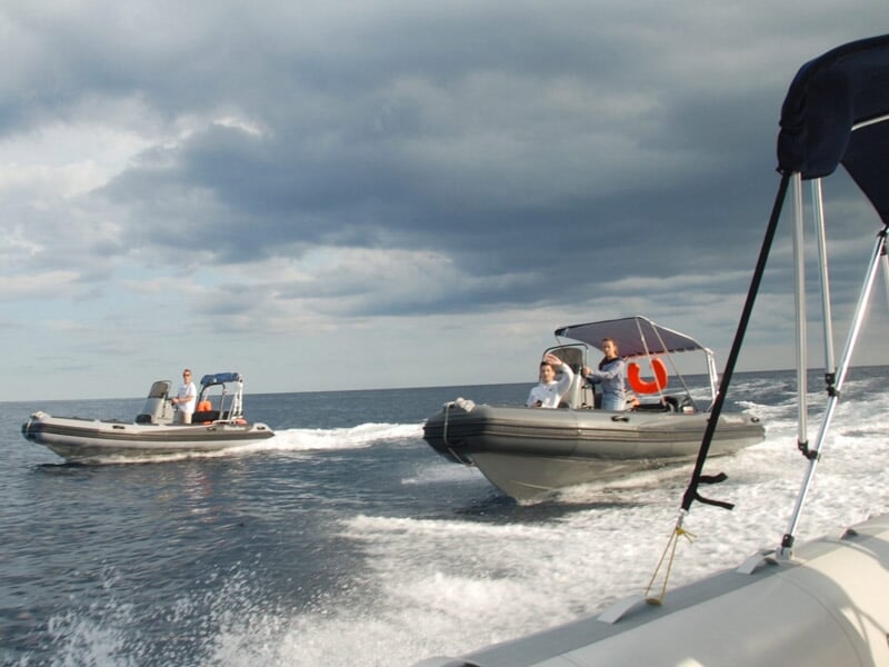 Deux bateaux pneumatiques rapides naviguant sur une mer agitée sous un ciel nuageux.