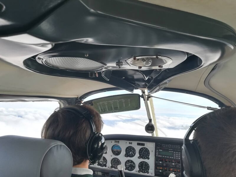 Intérieur d'un cockpit d'avion avec deux personnes portant des casques, concentrées sur les instruments de vol.