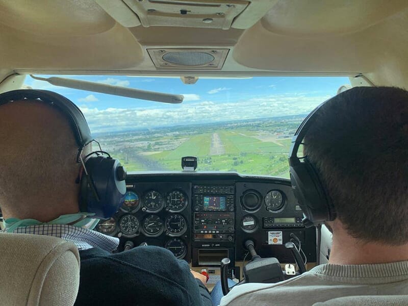 Un instructeur et son apprenti dans le cockpit d'un avion école approchent la piste d'atterrissage d'un aérodrome