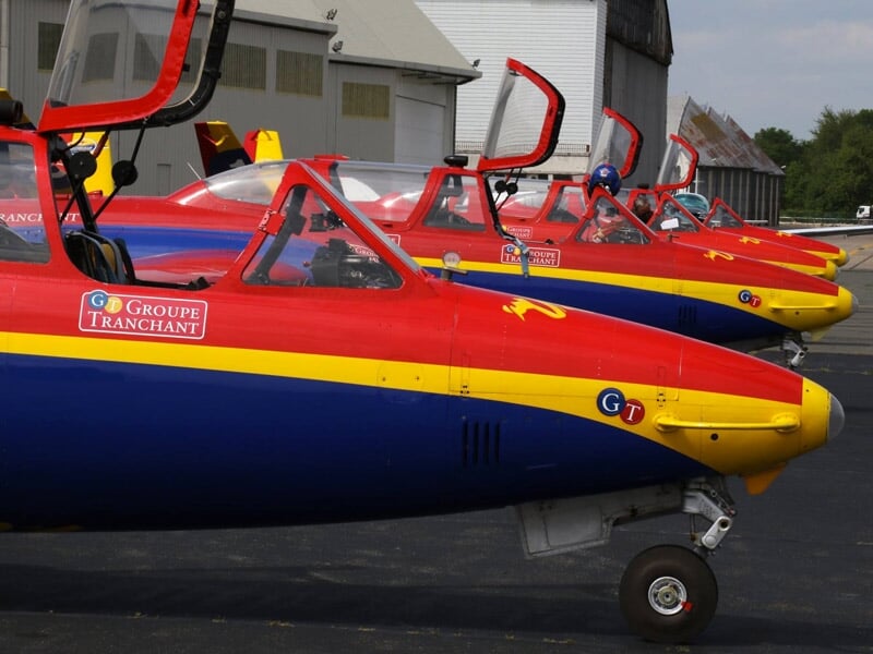 Des Fouga Magisters rouge, bleu et jaune sur le tarmac avec les cockpits ouverts