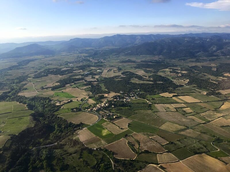 Vue aérienne d'une campagne avec des champs et des collines sous un ciel dégagé.