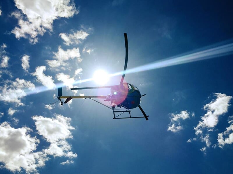 Hélicoptère volant avec le soleil et les nuages en arrière-plan.
