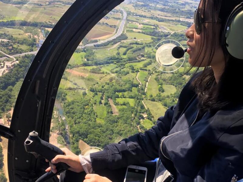 Femme pilotant un hélicoptère avec une vue panoramique de la campagne en contrebas