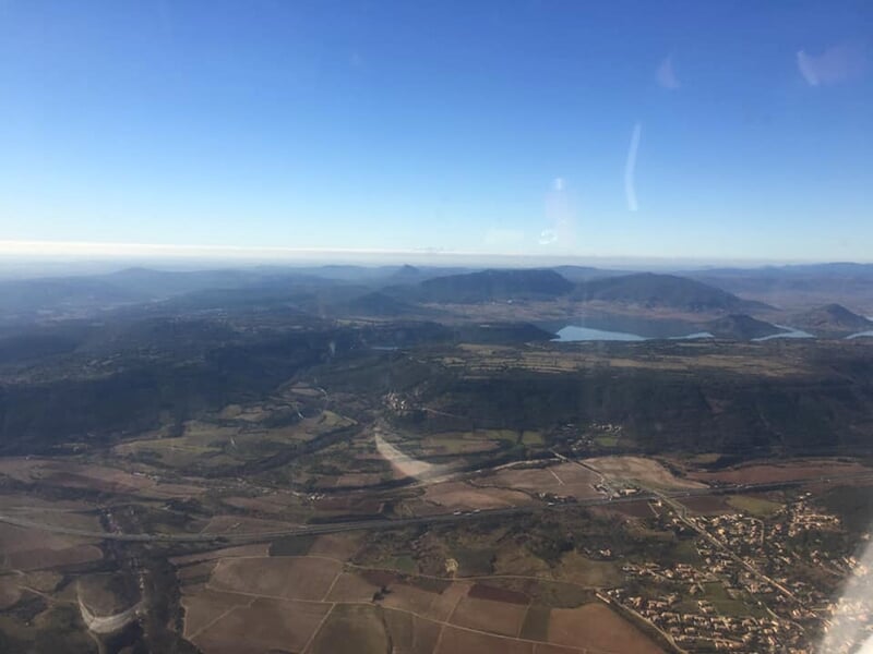 Vue aérienne d'un paysage vallonné avec des lacs et des collines sous un ciel dégagé.
