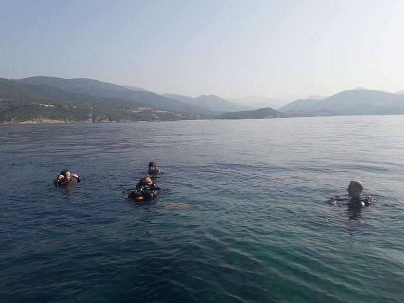 Trois plongeurs en combinaison noire flottant à la surface de l'eau calme en mer.