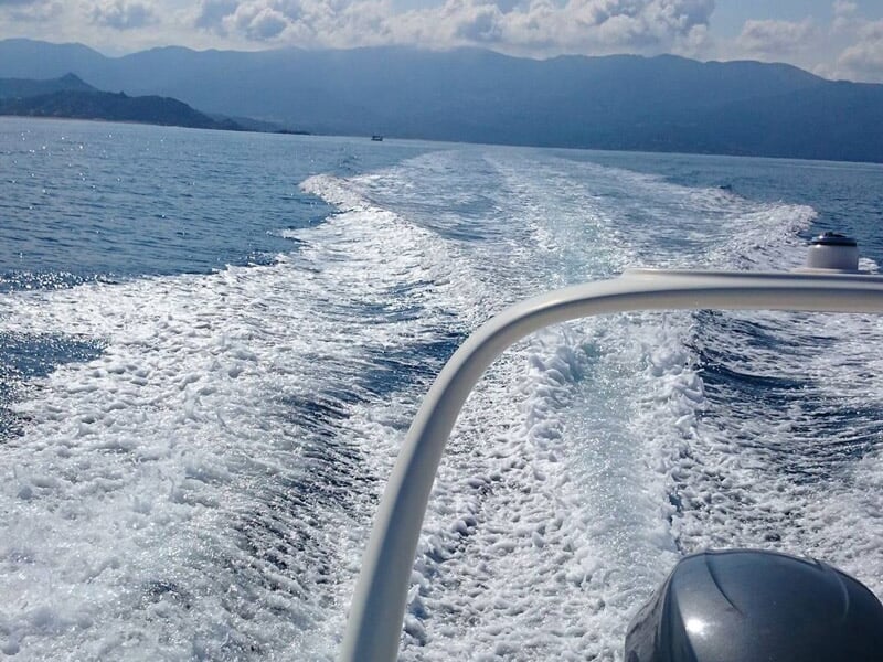 Sillage blanc laissé par un bateau rapide sur une mer calme sous un ciel partiellement nuageux.