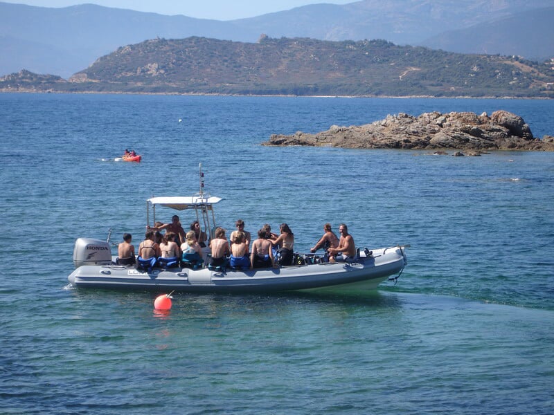 Groupe de plongeurs assis sur un bateau en mer, prêts pour une sortie de plongée sous-marine en Corse.