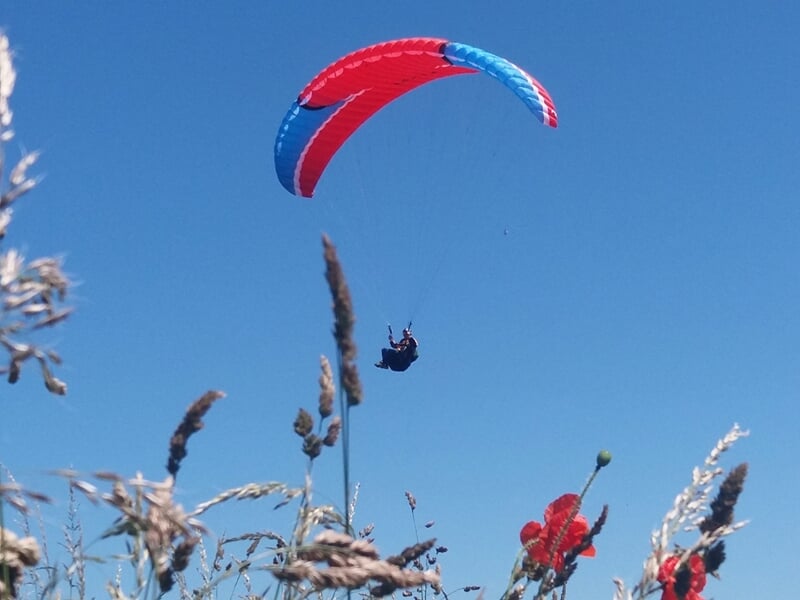Un parapente plane dans le ciel bleu à quelques mètres du sol