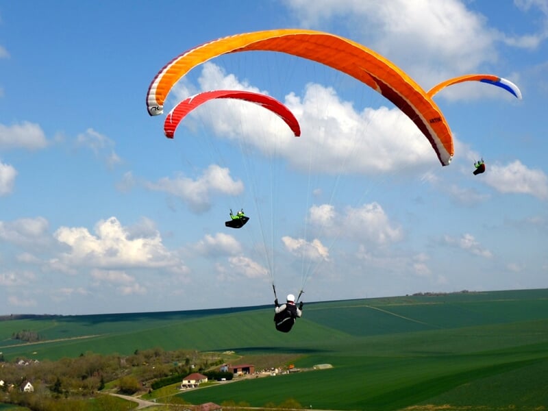 Trois parapentes volent au-dessus des champs à promixité de Paris