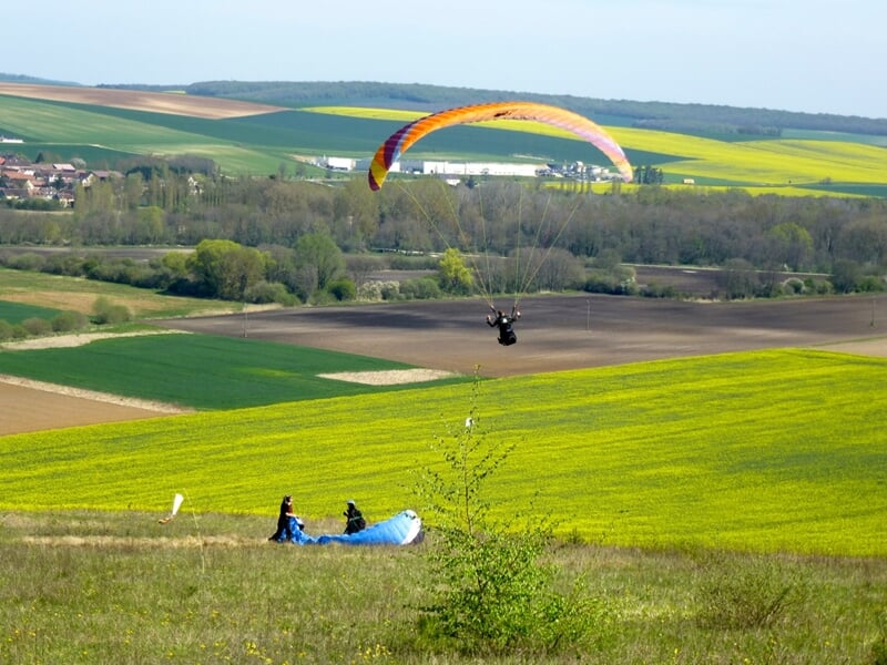 Un parapente s'élève dans le ciel depuis une pente école