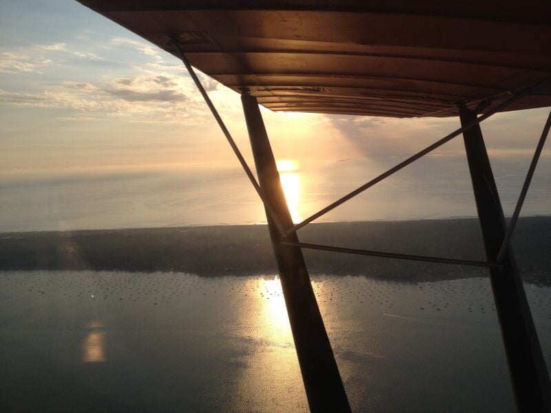 Coucher de soleil vu depuis un avion ultraléger motorisé au-dessus de l'océan et des dunes de sable.