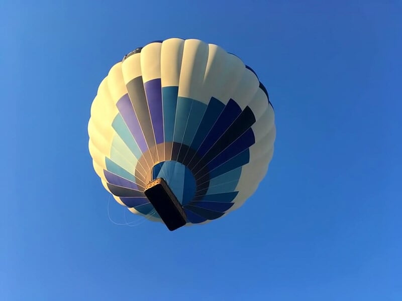 Montgolfière bleue et blanche vue du dessous, sur le ciel bleu vif