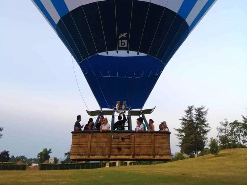 Montgolfière bleu marine et blanc avec des passagers dans la nacelle, prête pour le vol au crépuscule