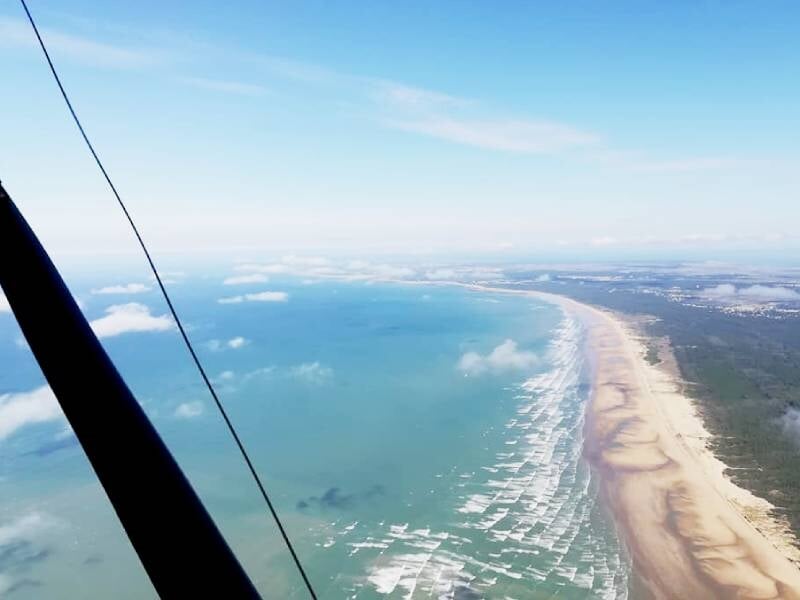 Vue aérienne d'une longue plage bordée par l'océan, prise depuis un avion ultraléger en vol au-dessus de Marennes.