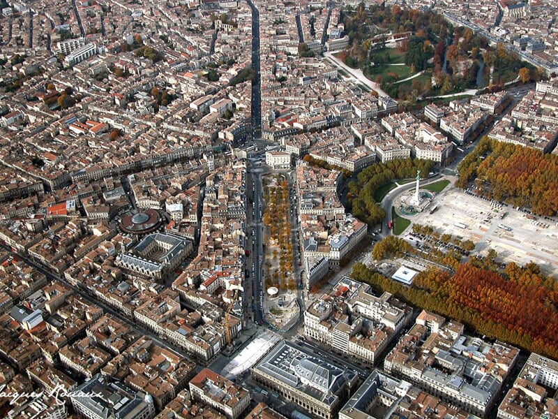 Vue aérienne d'une grande ville avec des rues en étoile, des bâtiments anciens et un parc arboré en automne.