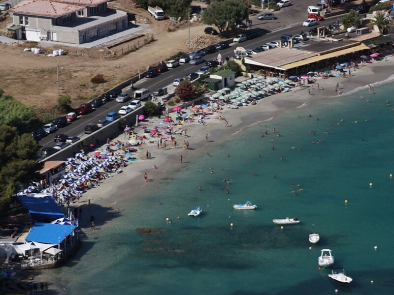 Vue aérienne d'une plage animée avec des parasols colorés et des baigneurs au bord de l'eau turquoise