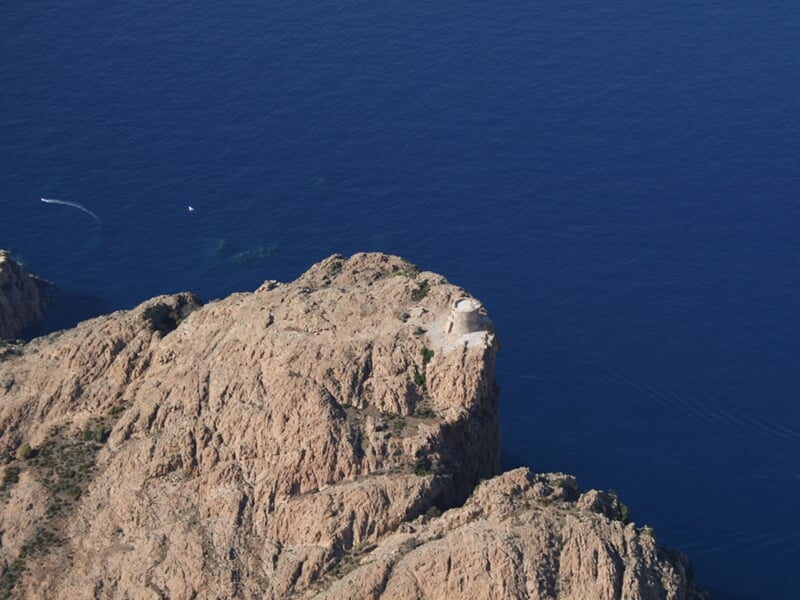 Vue aérienne d'une falaise rocheuse surplombant une mer d'un bleu profond sous un ciel clair